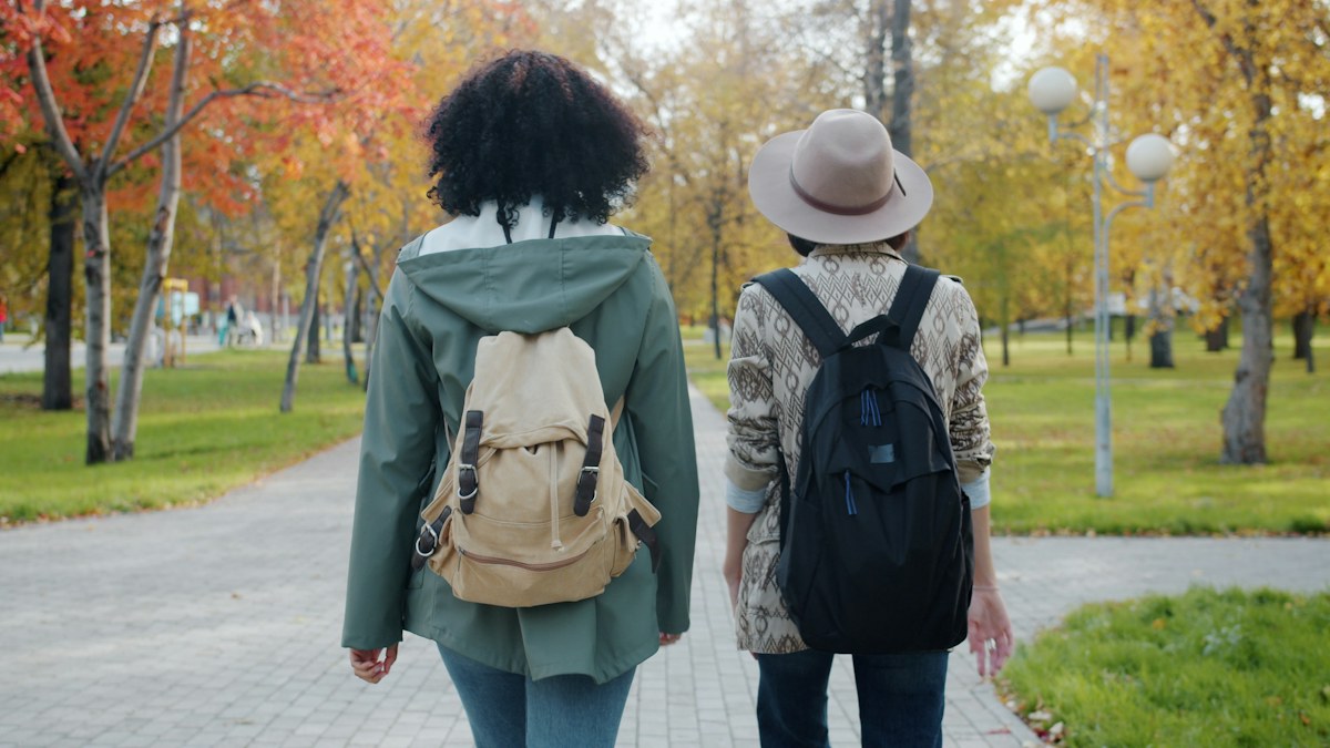 Two people walking side by side along a park path